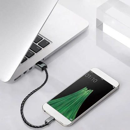 Bracelet chargeur USB en cuir noir branché à un ordinateur portable pour recharger un appareil.